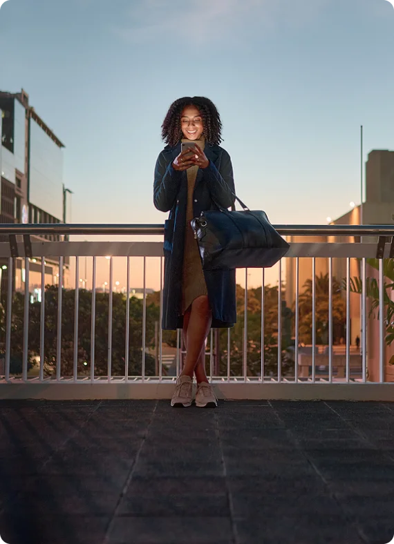 Eine Frau steht an einer Treppe in einer Stadt und sieht auf ihr Handy